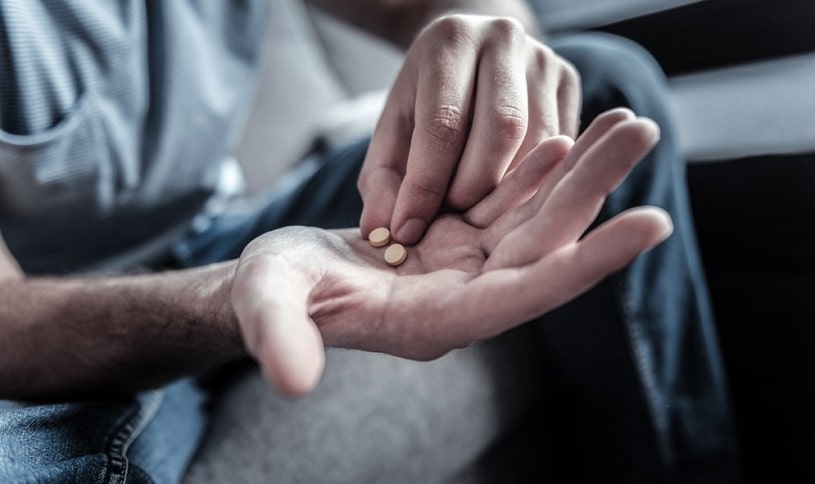 Man holding two pills in hand, is going to take them.