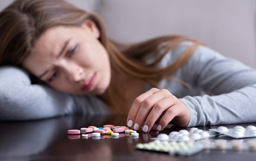Woman counting pills on the table.