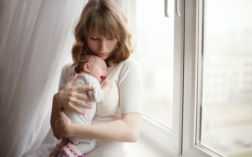 Crying baby in mother's hands.