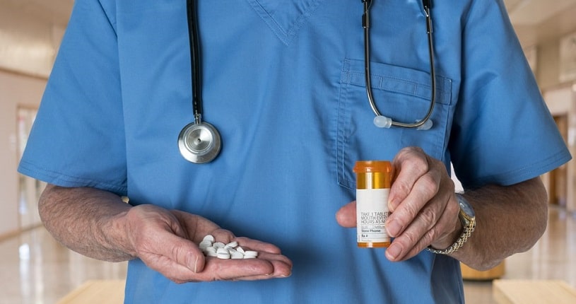 Male doctor holding dilaudid pills in the bottle.