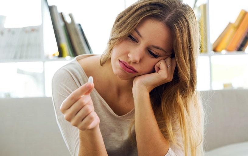 Depressed young woman during Halcion withdrawal holding a pill.
