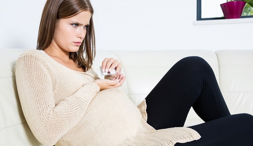 Pregnant woman with pills worried about Kratom side effects.