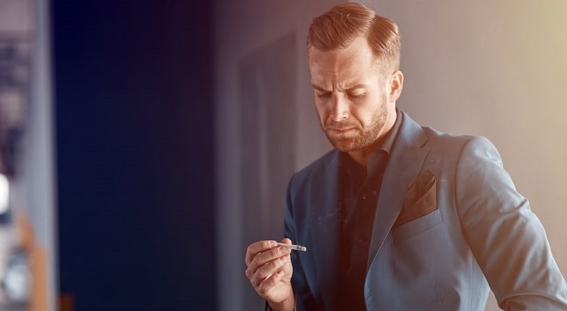 Man holding a cigarette and thinking about his bad habit.