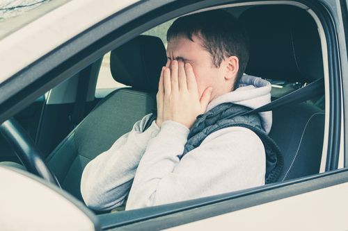 Driver driving vehicle while looking frustrated and angry.