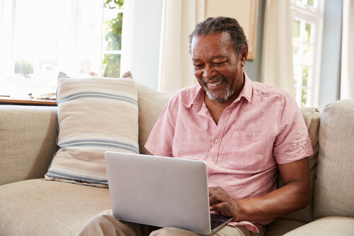 Senior Man Sitting On Sofa Using Laptop.