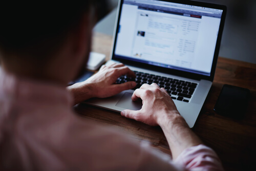 man's hands using a laptop at home.