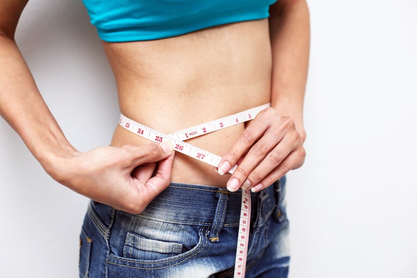 Woman measuring waistline with measure tape.