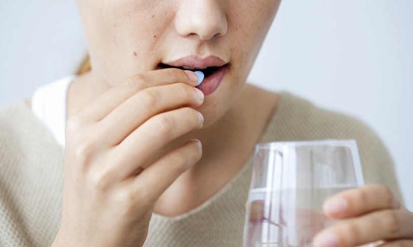 Young woman taking zoloft pill.