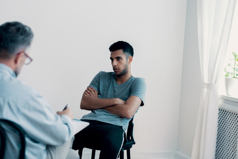An angry guy is sitting with folded hands.