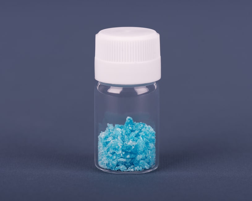 Blue crystals of bath salt in a glass jar.