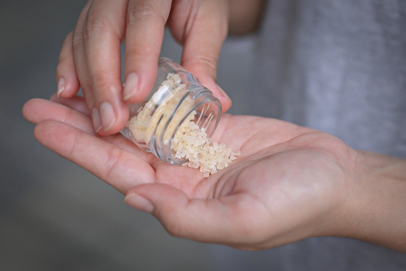 Someone sprinkles some yellow bath salt on their palm.