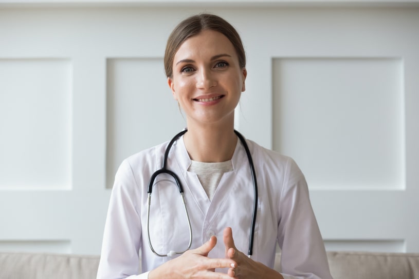 A woman in a white coat is standing with a stethoscope around her neck.