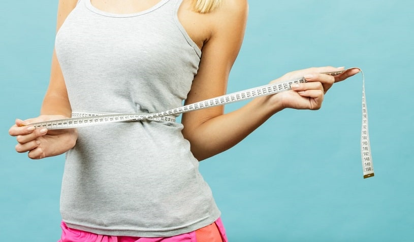 Woman is measuring her waist.