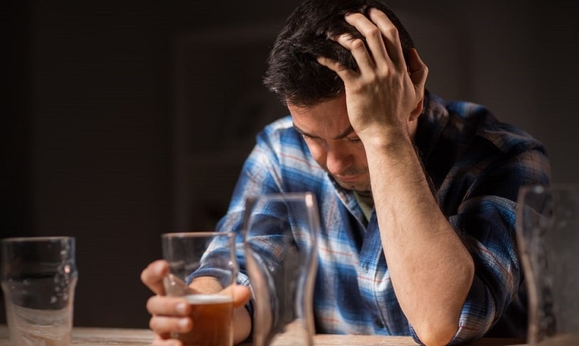 Man sitting at a table suffering from alcoholism.