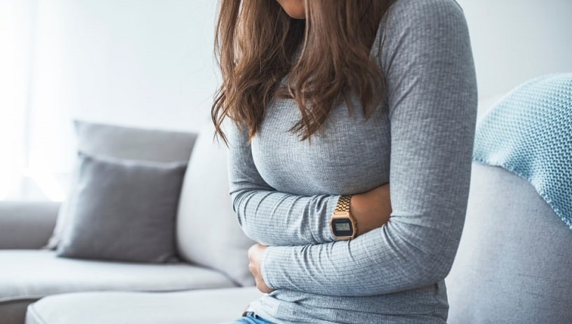 Woman on the sofa experiences constipation during caffeine withdrawal.