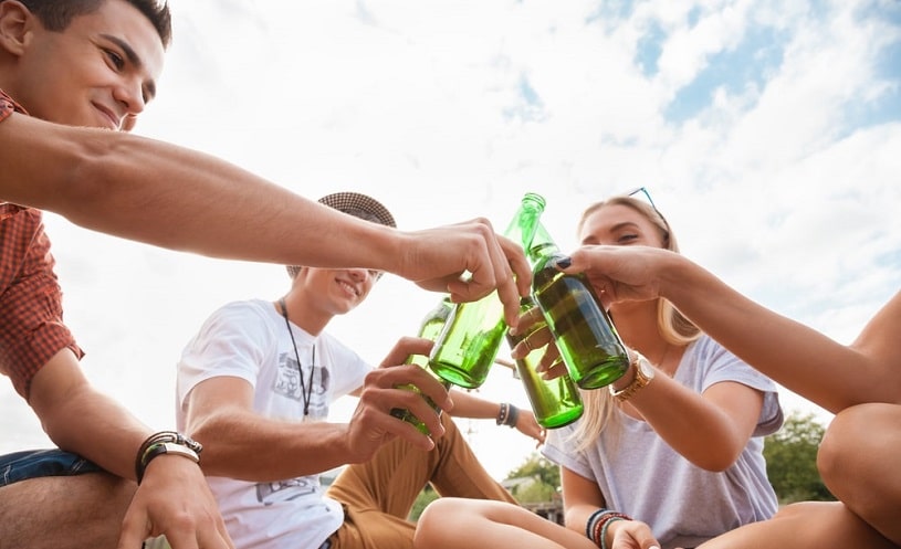 Teenagers drinking beer outdoors.