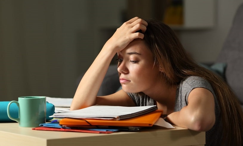 Teenager trying to study with books.